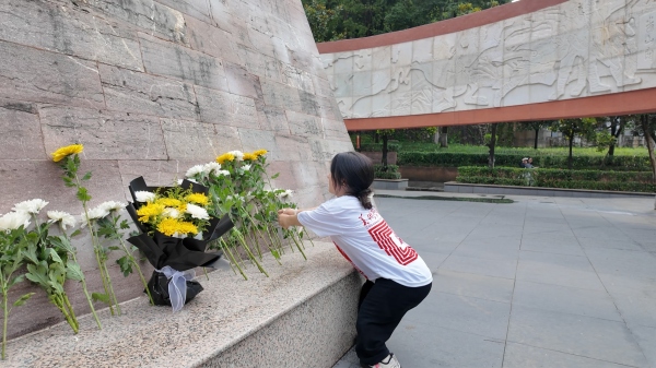 屈美芸在烈士纪念碑前献花。伟德国际英国美术学院供图